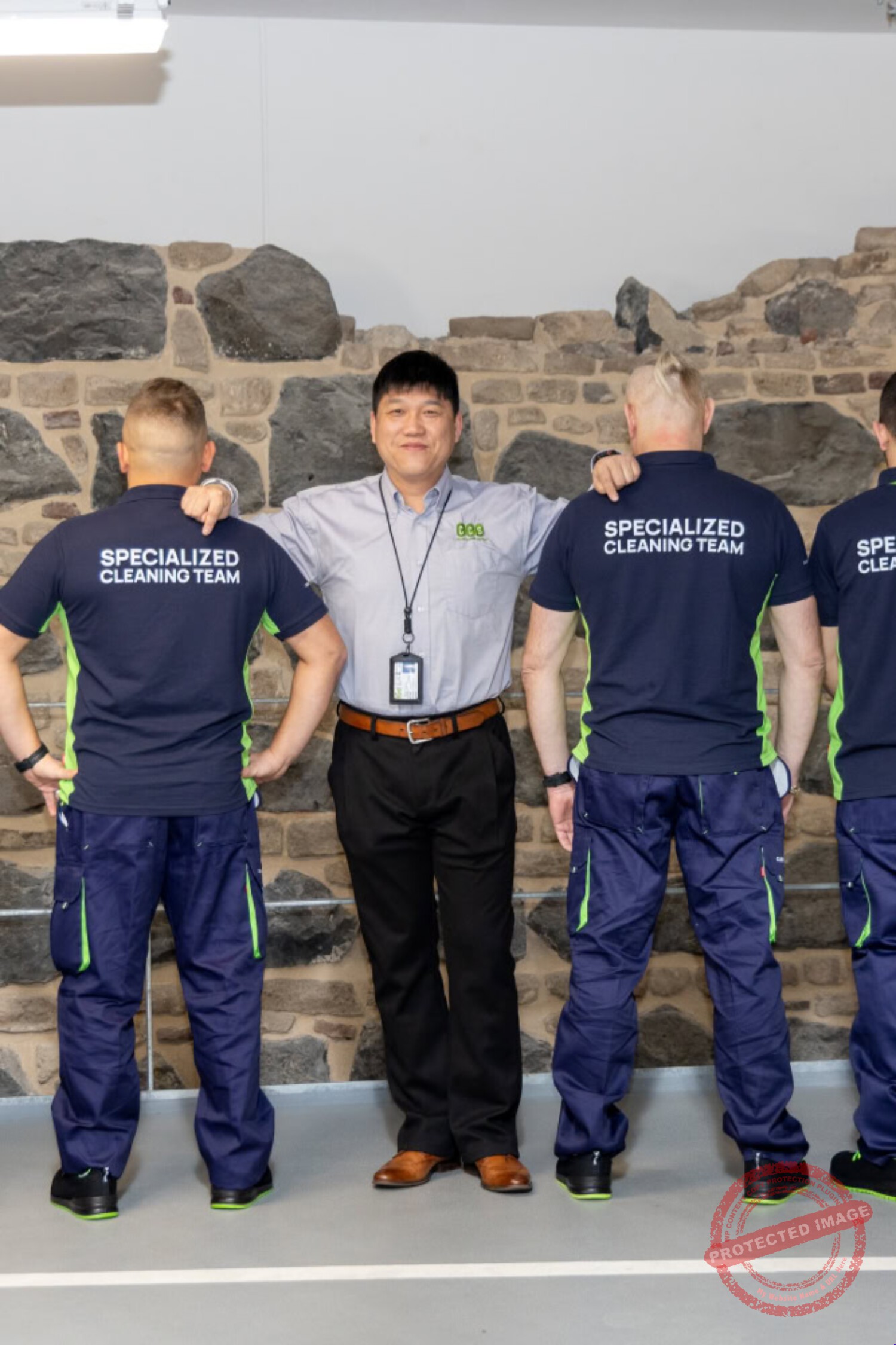Altes Reinigungsteam in blauen Uniformen mit "Specialized Cleaning Team" auf Rücken, professionell und teamorientiert.